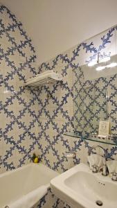 ソレントにあるグランド ホテル アミンタの青と白のタイル張りの壁のバスルーム(シンク付)