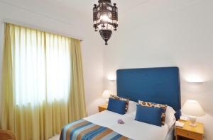 a bedroom with a blue and white bed and a chandelier at Grand Hotel Aminta in Sorrento