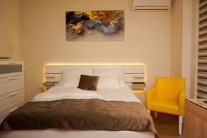 Un dormitorio con una cama y una silla amarilla. en Central Palace Apartmani - Pupinova palata, en Novi Sad
