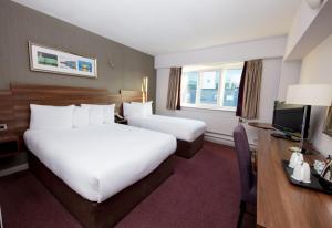 um quarto de hotel com duas camas e uma escrivaninha em Leonardo Hotel Cork em Cork