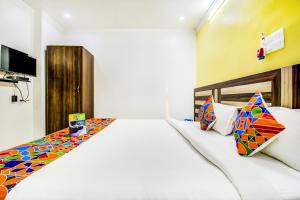 a bedroom with a large white bed with colorful pillows at FabHotel Grand Sheela in Patna