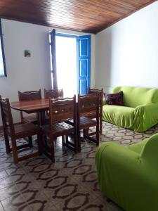 ein Wohnzimmer mit einem Tisch und einer grünen Couch in der Unterkunft Casa da Praça Morro de São Paulo in Morro de São Paulo