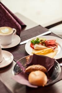 una mesa con platos de comida y una taza de café en DasSchaffers - MeinWohlfühlhotel, en Bad Mergentheim