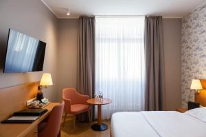 a hotel room with a bed and a desk and a table at Hotel Perrin - former Carlton in Luxembourg