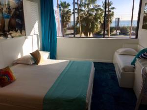 a bedroom with a bed and a window with palm trees at SoBlue Hôtel in Antibes