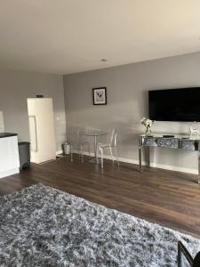 a living room with a table and a flat screen tv at COACHMAN COTTAGE OUTSIDE HOT TUB in Beith