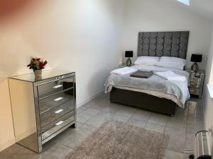 a bedroom with a large bed with a dresser and a bed sidx sidx sidx at COACHMAN COTTAGE OUTSIDE HOT TUB in Beith