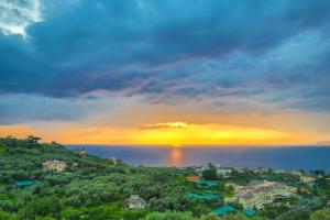 a sunset over the water with houses on a hill at Grand Hotel Aminta in Sorrento