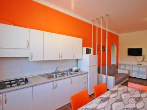 a kitchen with white cabinets and an orange wall at Residence Il Pavone in Marina di Campo