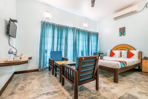 Schlafzimmer mit einem Bett, einem Schreibtisch und einem TV in der Unterkunft FabExpress Santhi Inn, Promenade Beach in Puducherry
