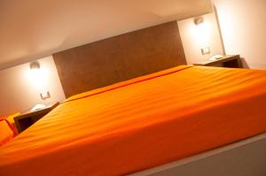 un grande letto arancione in una camera da letto con due luci di Torre Lapillo Centro GMA Tourism a Torre Lapillo