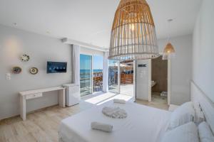 a white room with a bed and a chandelier at Raffaello Beach in Faliraki