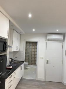uma cozinha com armários brancos, um lavatório e uma porta em WILLMARK 2 em Salamanca