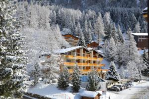um hotel nas montanhas com árvores cobertas de neve em Hotel Alex em Leukerbad