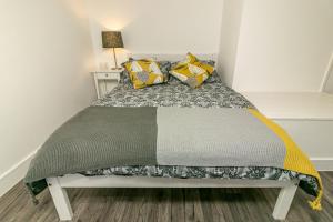 a small bedroom with a bed with yellow pillows at Denby Lodge in Letchworth