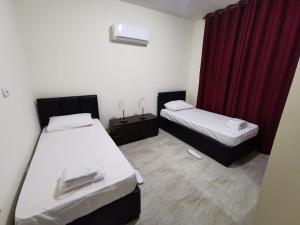 twee bedden in een kamer met een rood gordijn bij Margarita Hotel in Amman