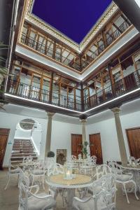 una camera con tavoli e sedie bianchi e un balcone di Alvar Fañez a Úbeda