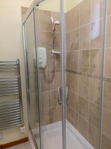 a shower with a glass door in a bathroom at Hayfield Apartment in Lossiemouth
