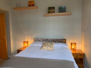 a bedroom with a white bed with two lamps on tables at Hayfield Apartment in Lossiemouth