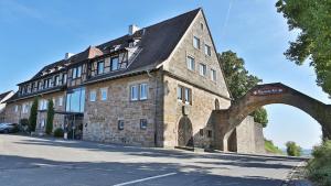 - un grand bâtiment en pierre avec une arche en face dans l'établissement Hotel Leinsweiler Hof, à Leinsweiler