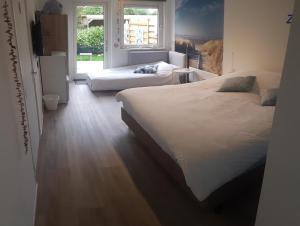a bedroom with two beds and a window at Duin en Zee Texel in De Koog