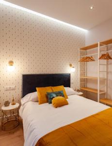una camera da letto con un grande letto bianco con cuscini gialli di MIMA Suites Chueca a Madrid