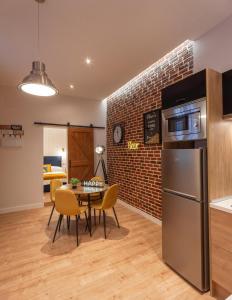 una cucina e una sala da pranzo con tavolo e muro di mattoni di MIMA Suites Chueca a Madrid