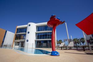 a building with a red squid statue in front of a pool at SoBlue Hôtel in Antibes