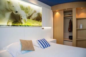 a bed room with a white bed and a white bedspread at Marineland Hôtel in Antibes