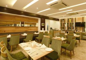 a restaurant with wooden tables and green chairs at GCC North Side in Mumbai