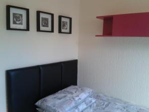 a bedroom with a black headboard and three pictures on the wall at Avenue Road in Gateshead
