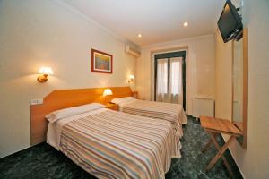 Habitación de hotel con 2 camas y TV de pantalla plana. en Hostal Prim, en Madrid