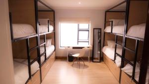 a room with bunk beds with a chair and a window at Explorer Backpackers in Johannesburg