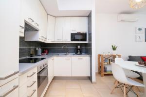 Una cocina con gabinetes blancos y una mesa con sillas. en Alohamundi San Julián, en Sevilla 10 fotos más