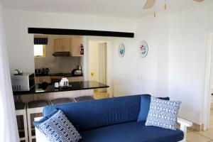 Kaliva 364 at Club Mykonos in Langebaan في لانجيبان: غرفة معيشة مع أريكة زرقاء ومطبخ