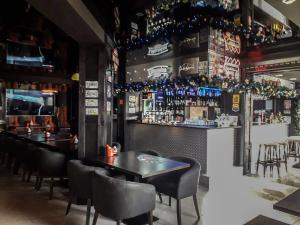 a bar with tables and chairs and bottles on the wall at Elijos apartamentai in Šventoji