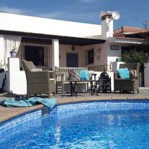 a pool with chairs and a table next to a house at Casa al Cerro in Alora