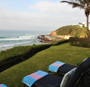 une pelouse avec deux chaises longues et l'océan dans l'établissement 1 Marichel, à Ballito