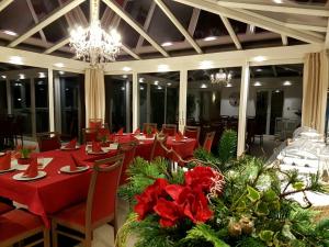 a restaurant with red tables and chairs and a chandelier at Gästehaus Staudenschloss in Mickhausen
