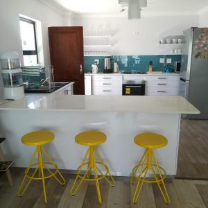 a kitchen with yellow stools at a white counter at Explorer Backpackers in Johannesburg