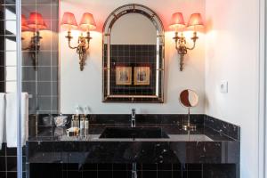 ein Bad mit einem schwarzen Waschbecken und einem Spiegel in der Unterkunft Dear Lisbon - Bordalo Palace Chiado in Lissabon