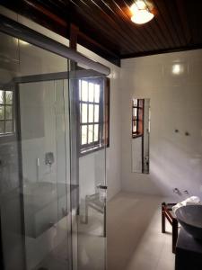 a bathroom with a glass shower and a sink at Pousada Casarão in Jaraguá do Sul