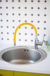 a sink in a kitchen with a yellow faucet at Fruza family apartment in Riga in Rīga