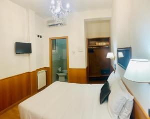 a bedroom with a white bed and a chandelier at Hotel Cassia in Rome