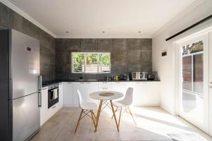 a kitchen with white cabinets and a table and chairs at Casa Casa - Studio in Durban