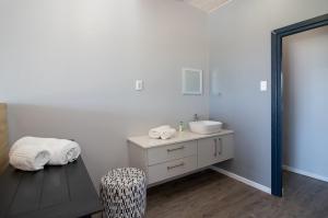 a white bathroom with a sink and a chair at Sky Blue Guest House in Kenton on Sea