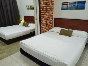 a bedroom with two beds and a brick wall at The Octagon Ipoh - Home Stay in Ipoh