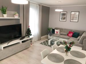 ein Wohnzimmer mit einem Sofa und einem TV in der Unterkunft Apartamenty Cypryjskie 2 sypialnie in Koszalin