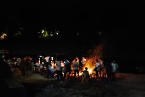 a group of people standing around a fire at night at Baantantara in Suan Phung