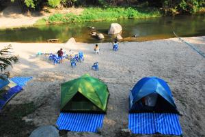 a group of tents on a beach next to a river at Baantantara in Suan Phung